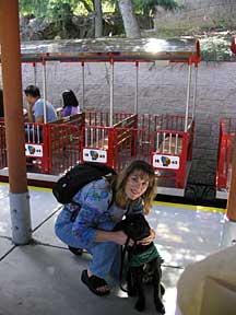 Marikay and Cynthia posing in front of a small red train with open bench seats.