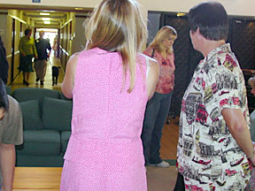 Marikay and Bev watch Justin and Cynthia walk down hallway to lounge.